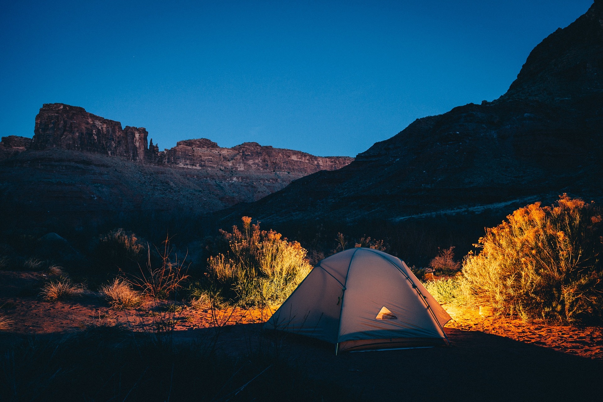 Beleuchtetes Zelt vor Hügelkette in der Nacht