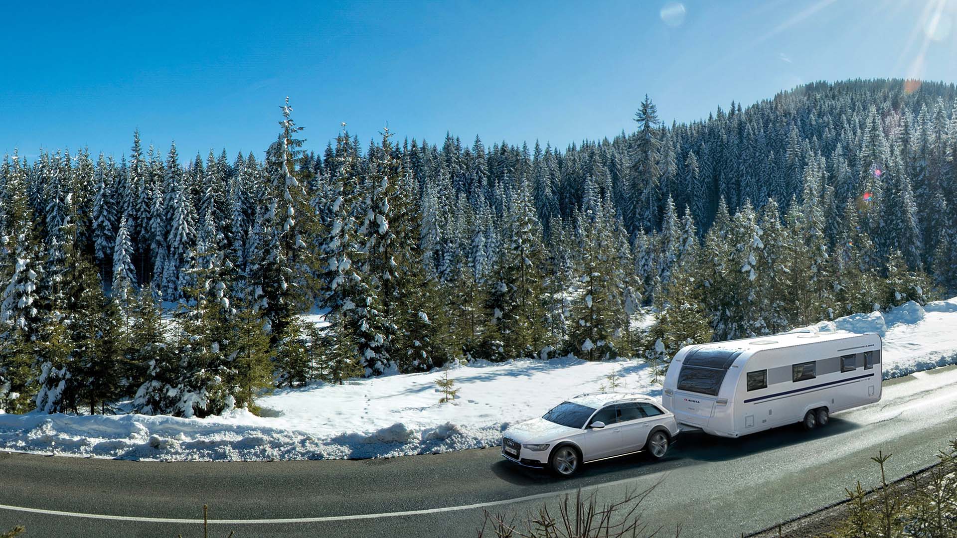 Adria Alpina-Wohnwagen in bezaubernder Winterlandschaft, gezogen von einem weißen SUV